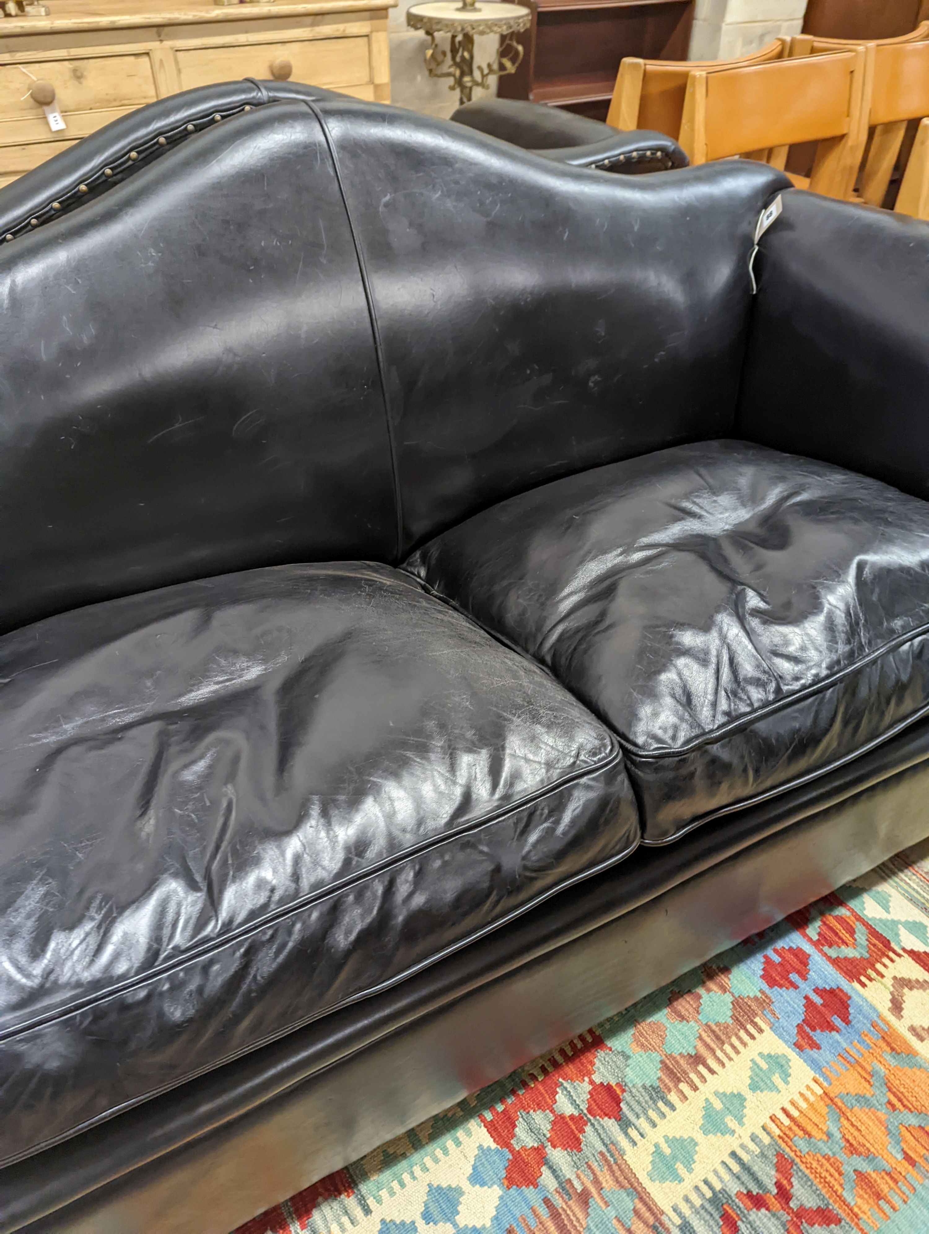 A pair of black leather scroll arm two seater settees on flat bun feet, length 184cm, depth 80cm, height 93cm